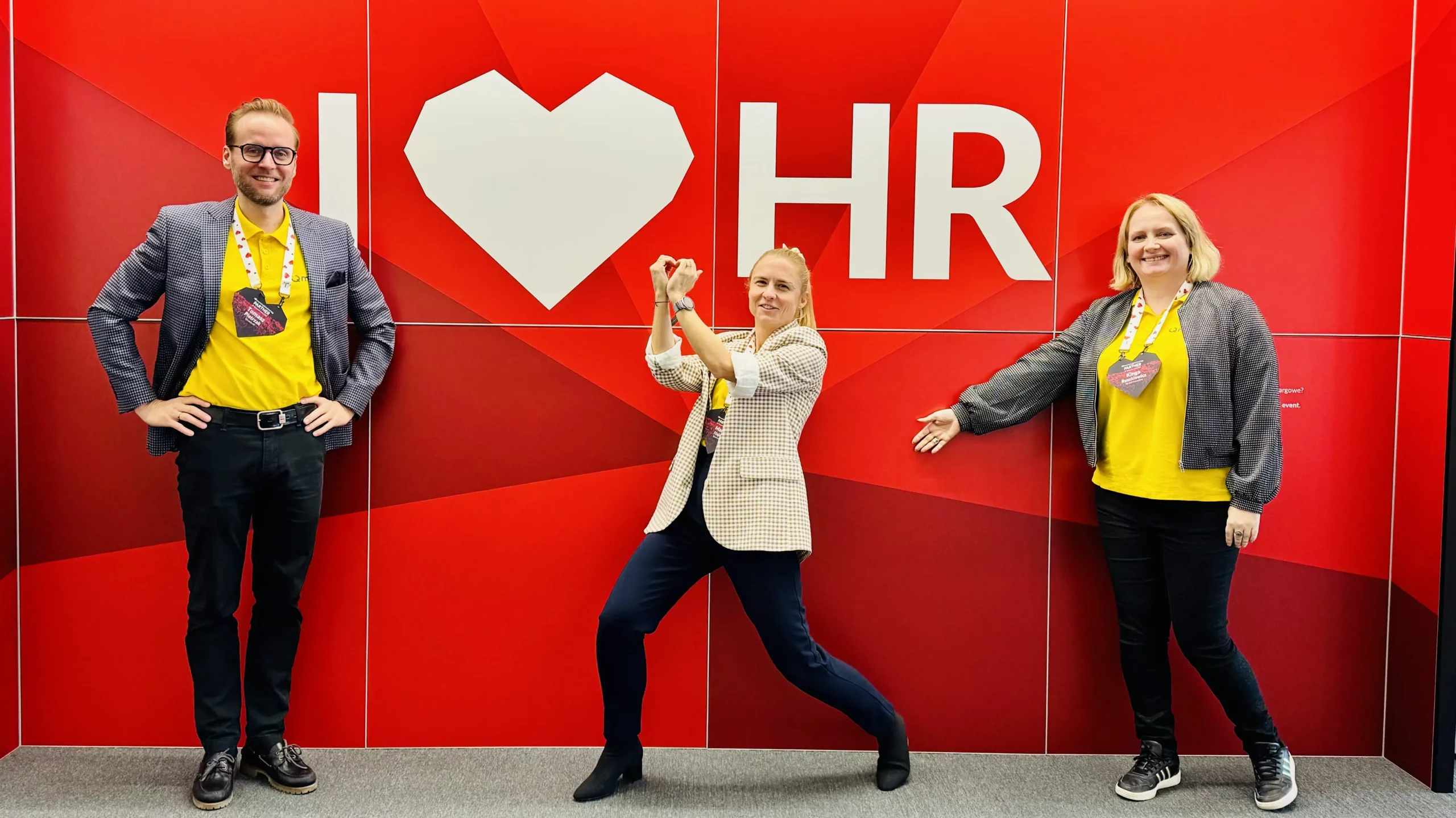 Zespół Qmatch HR na targach HR, przy ścianie z napisem I love HR